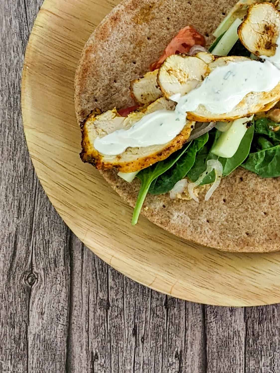 zhug feta hummus chicken wrap sitting open faced on a bamboo plate